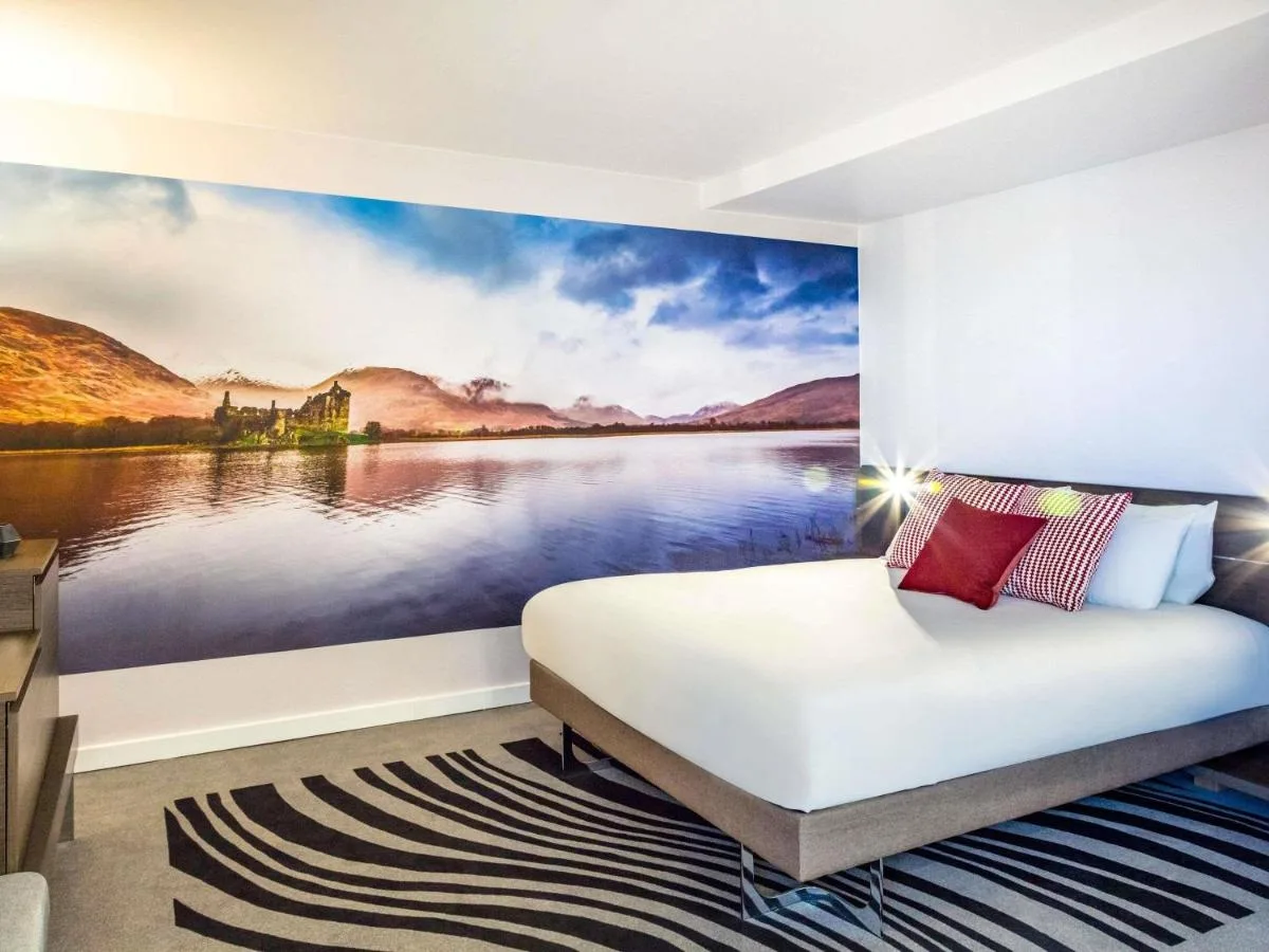 Bedroom with a castle-view painting at Novotel Edinburgh Centre